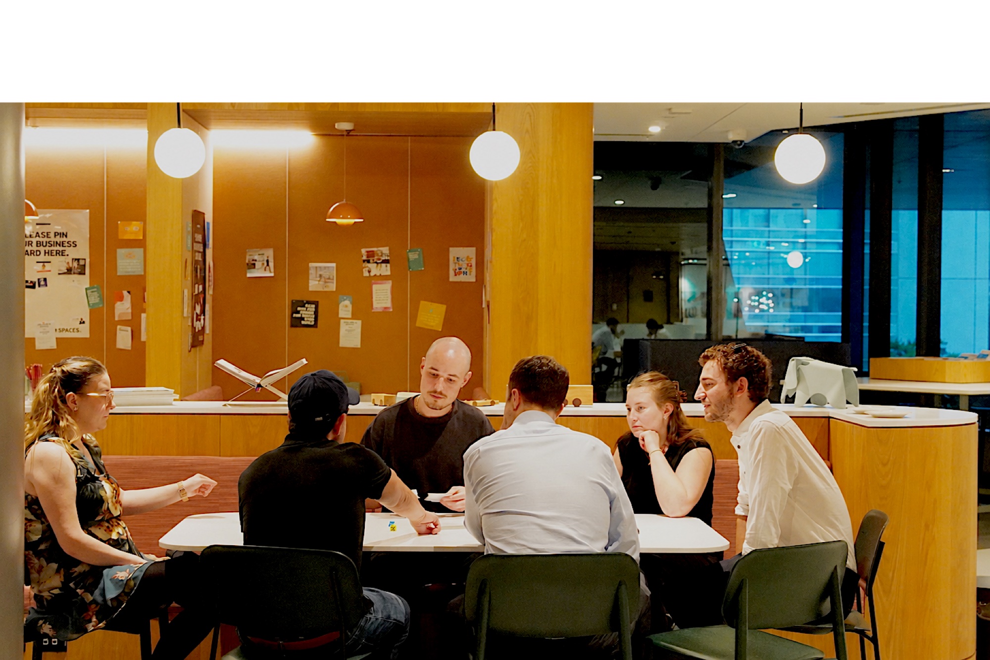 OFO Collective — six people around a table in a coworking space, mid-conversation.